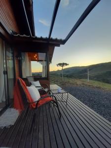 a wooden deck with two chairs on a house at Pousada Recanto da Cascata - Cabana Platano in São Joaquim
