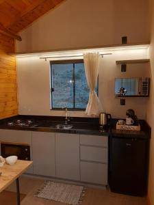 una pequeña cocina con fregadero y ventana en Pousada Recanto da Cascata - Cabana Platano, en São Joaquim