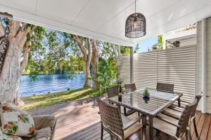 una sala da pranzo con tavolo, sedie e vista sull'acqua di Noosa Entrance Waterfront Resort a Noosaville