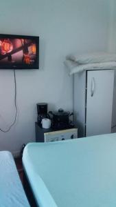 a room with a bed and a refrigerator and a tv at Antonia Hospedaria 2 in Búzios
