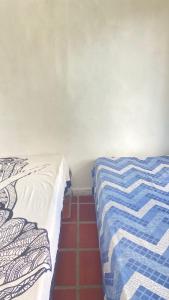a bedroom with a bed with a blue and white blanket at Antonia Hospedaria 2 in Búzios