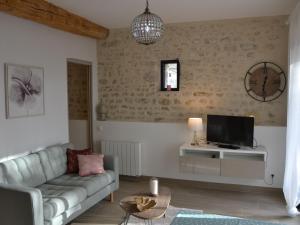 ein Wohnzimmer mit einem Sofa und einem TV in der Unterkunft Gîte Chilleurs-aux-Bois, 2 pièces, 2 personnes - FR-1-590-276 in Chilleurs-aux-Bois
