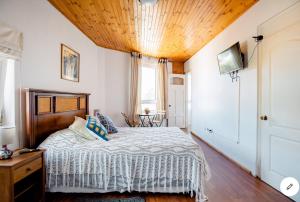 1 dormitorio con 1 cama con techo de madera en Hostal lala porteña vista al mar, baño privado y desayuno en Valparaíso