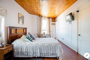 1 dormitorio con 1 cama con techo de madera en Hostal lala porteña vista al mar, baño privado y desayuno, en Valparaíso