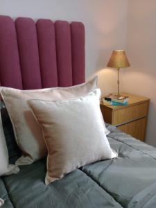 a bed with pillows and a table with a lamp at My House in El Calafate. in El Calafate