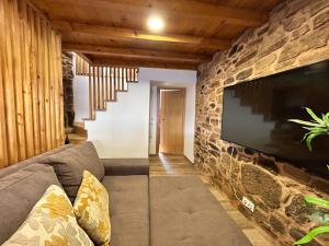 uma sala de estar com uma parede de pedra e uma televisão em Casa d'avó Coragem em Seia