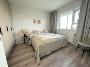 a white bedroom with a bed and a window at New Selfoss Apartment - Stylish & Modern in Selfoss