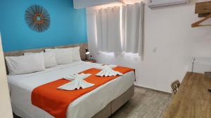 1 dormitorio con 1 cama grande con sábanas de color naranja y blanco en Pousada Portomares, en Porto de Galinhas