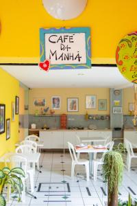 un restaurante con mesas y sillas blancas y una pared amarilla en Pousada Portomares, en Porto de Galinhas