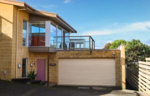 a house with a garage door and a balcony at Tides Port Fairy in Port Fairy