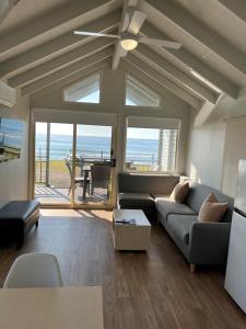 Blue Lagoon Beach Resort في ذا إينترانس: غرفة معيشة مع أريكة ومروحة سقف
