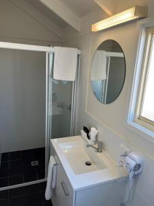 a bathroom with a sink and a shower with a mirror at Blue Lagoon Beach Resort in The Entrance