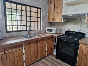 a kitchen with a stove and a sink and a microwave at MercedesHouse in Hermosillo