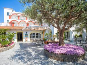 a tree in front of a house with purple flowers at Hotel La Scogliera in Ischia