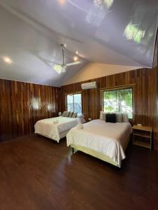 two beds in a room with wood paneling at Grand Park Manuel Antonio - Adults Only in Manuel Antonio