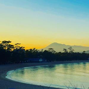 un coucher de soleil sur une plage avec une montagne en arrière-plan dans l'établissement 洲本家　SUMOTOYA, à Sumoto