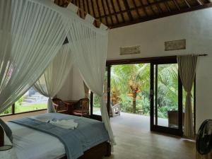 una camera da letto con un letto con tende bianche di Mambul Garden Private Villa a Sangeh