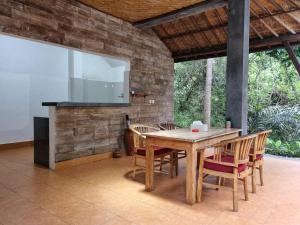 un tavolo in legno con sedie e una TV su un patio di Mambul Garden Private Villa a Sangeh