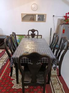 une table à manger, des chaises, une table et une horloge dans l'établissement Homestay Kesang Sungai Rambai, à Kampong Sungai Rambai