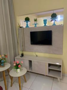 a living room with a television on a wall at Casa próximo da praia in Prado