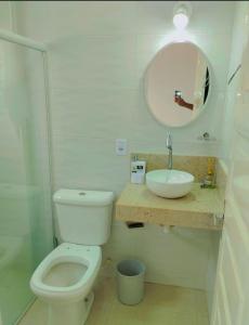 a bathroom with a toilet and a sink and a mirror at Duplex encantador em Guarapari-ES in Guarapari