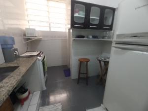 a small kitchen with a refrigerator and a stool at Apartamento para até 05 pessoas no centro in Teresópolis