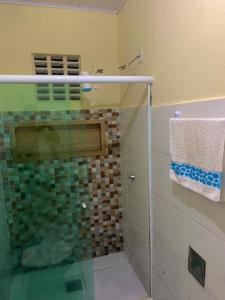 a bathroom with a glass shower with a towel at Casa próximo da praia in Prado
