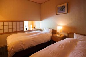 a hotel room with two beds and a lamp at Kurobe UnazukiOnsen Togen in Kurobe