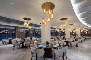 una sala da pranzo con tavoli, sedie e lampadari a braccio di White Swan Hotel Taizhou a Taizhou