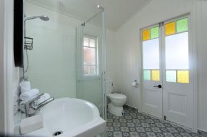 a white bathroom with a tub and a toilet at Pandanus House in Bargara +21 photos