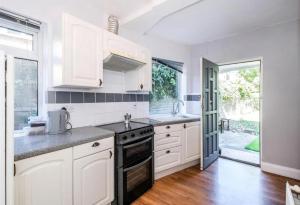 a kitchen with white cabinets and a stove top oven at Walthamstow 1 bed in London