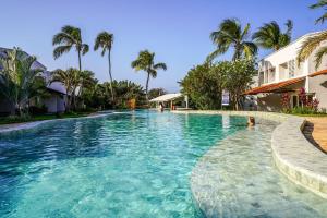 a swimming pool with blue water and palm trees at Casa Pipa Atlantico in Pipa