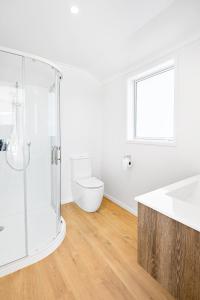 a white bathroom with a shower and a toilet at Whiti Whare in Whitianga