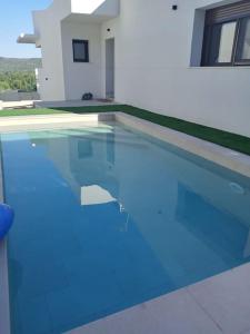 a swimming pool with blue water in front of a house at Casa nueva a pie de la Sierra de Guadarrama in Moralzarzal