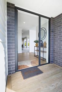 a pivot door in a room with a brick wall at Whiti Whare in Whitianga