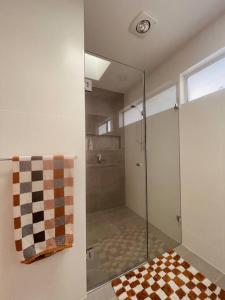 een badkamer met een glazen douche en een geruit tapijt bij Northern Beaches Oasis in Mona Vale