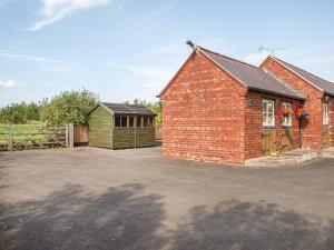 a brick building with a garage and a fence at Orchard View in Minsterley