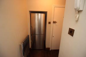 a stainless steel refrigerator in a hallway next to a door at Paddington Patio Apartment in London