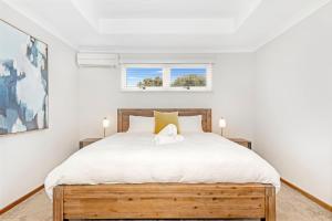 a bedroom with a wooden bed with white sheets at Ashdene Busselton in Busselton