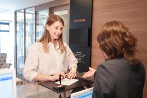 a woman standing at a counter talking to a customer at HOTEL Cargo Shinsaibashi in Osaka
