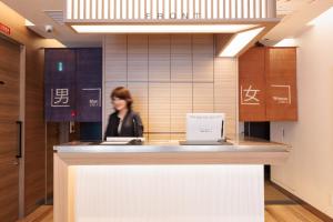 Una donna sta in piedi davanti a un bancone in un atrio di HOTEL Cargo Shinsaibashi ad Osaka