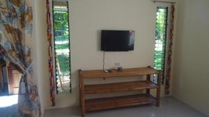 Habitación con TV y estante con TV. en ACACIA'S Cottages mit Starlink Wifi, en Mambajao