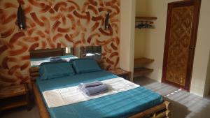 um quarto com uma cama com lençóis azuis e uma parede em ACACIA'S Cottages mit Starlink Wifi em Mambajao