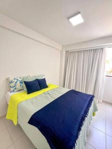 a bedroom with a bed with blue and yellow sheets at Muro Alto - Flat Completo MANA Resort in Porto De Galinhas