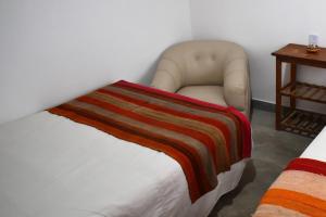 - une chambre avec une chaise et une couverture sur un lit dans l'établissement CASITA MUNAY - Cabaña en Huacalera - Quebrada de Humahuaca - Jujuy, à Huacalera