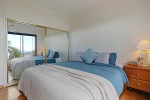 a bedroom with a large bed and a large mirror at Pambula Family Beach House in Pambula Beach
