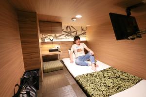 a person sitting on a bed in a room at HOTEL Cargo Shinsaibashi in Osaka