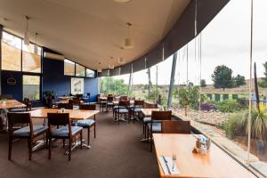 un restaurante con mesas, sillas y ventanas grandes en Station Motel, en Parkes