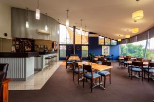 un restaurante con mesas y sillas de madera y ventanas en Station Motel, en Parkes