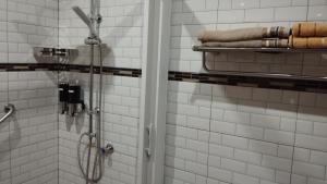 a shower in a white tiled bathroom with towels at Touch the Wind in Chaiyaphum
